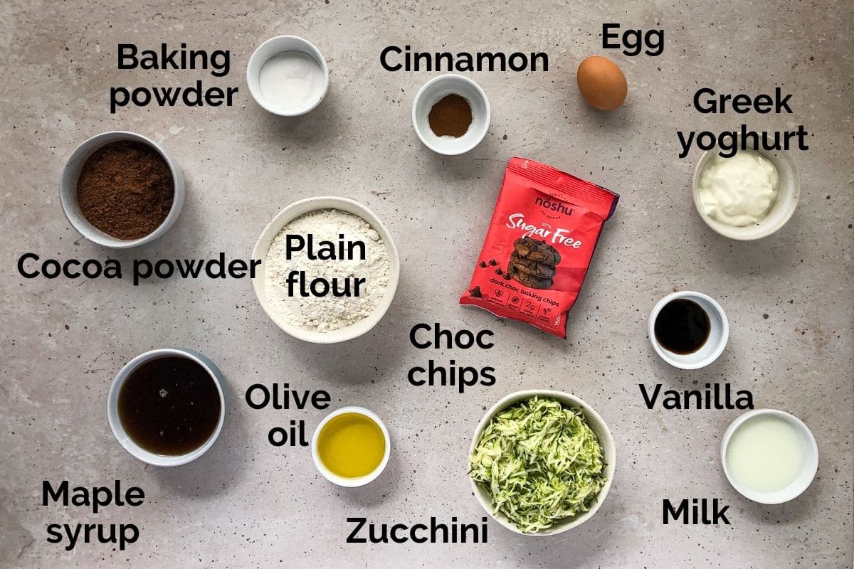 all ingredients for chocolate zucchini muffins, laid out on a table.