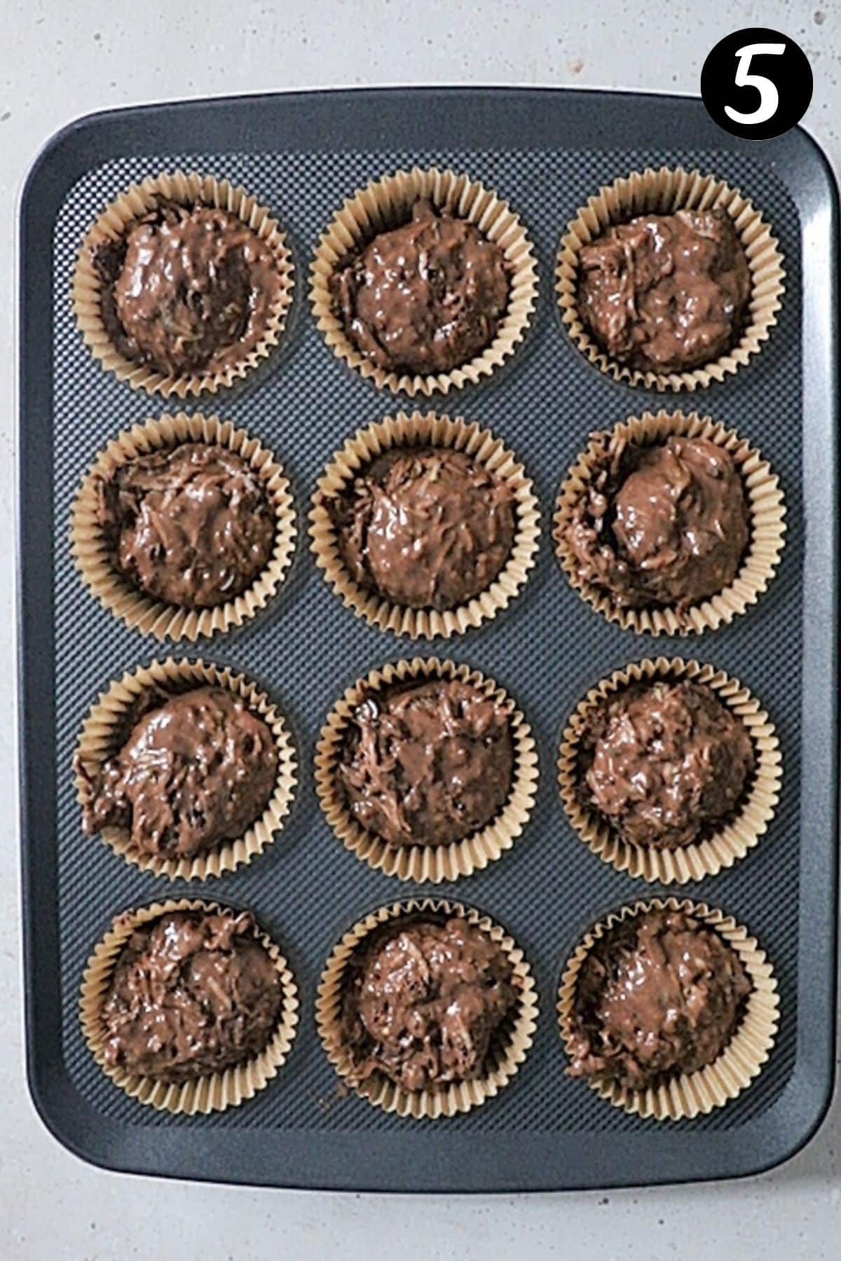 muffin batter in a muffin tray with paper cases.