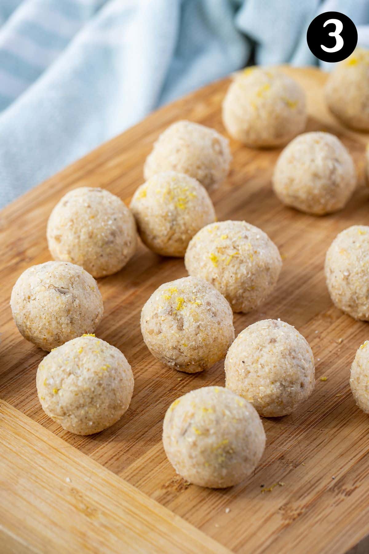 lemon bliss balls rolled out on a wooden board.