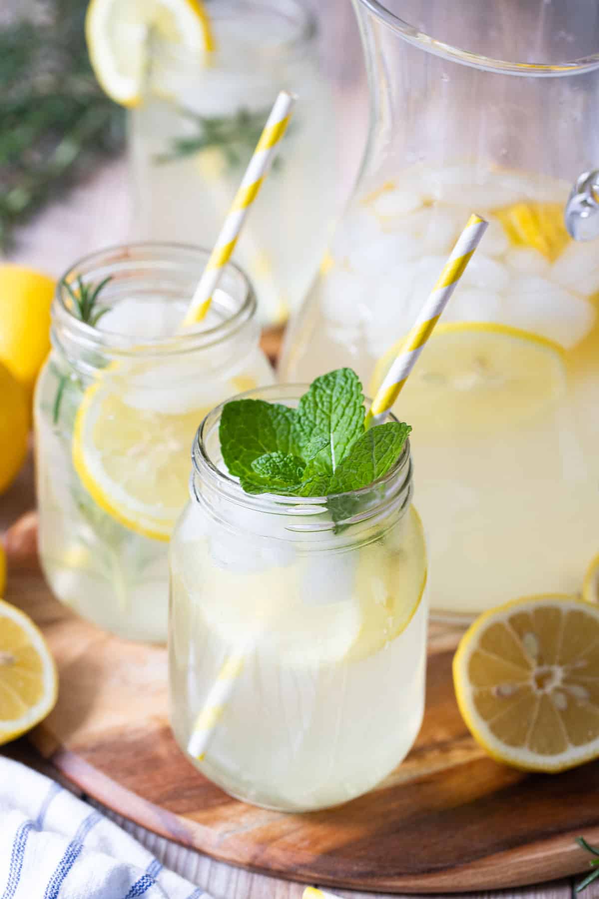 a jug of cordial on a wooden platter with glasses and lemon slices.