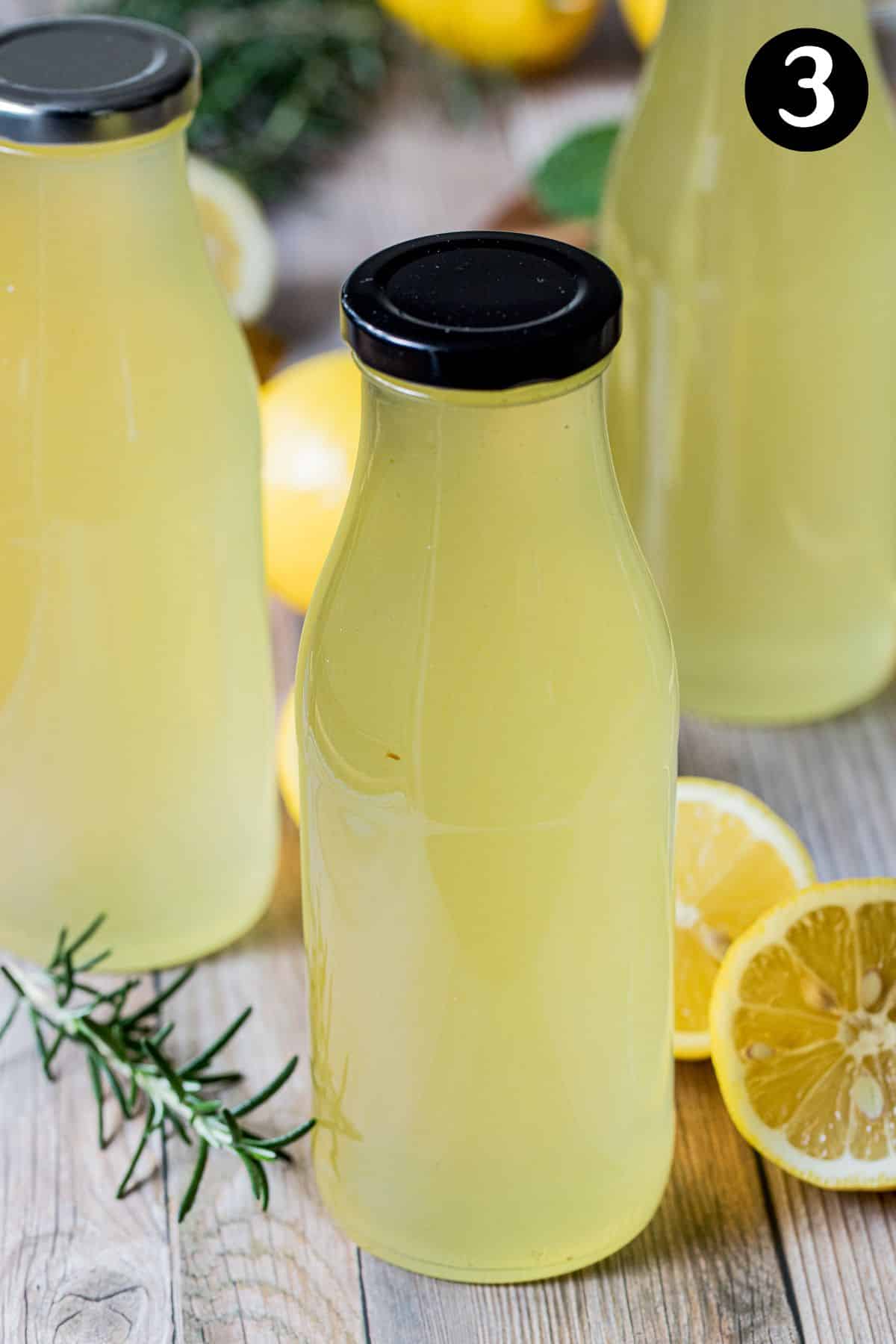 glass bottles containing lemon cordial on a wooden table.