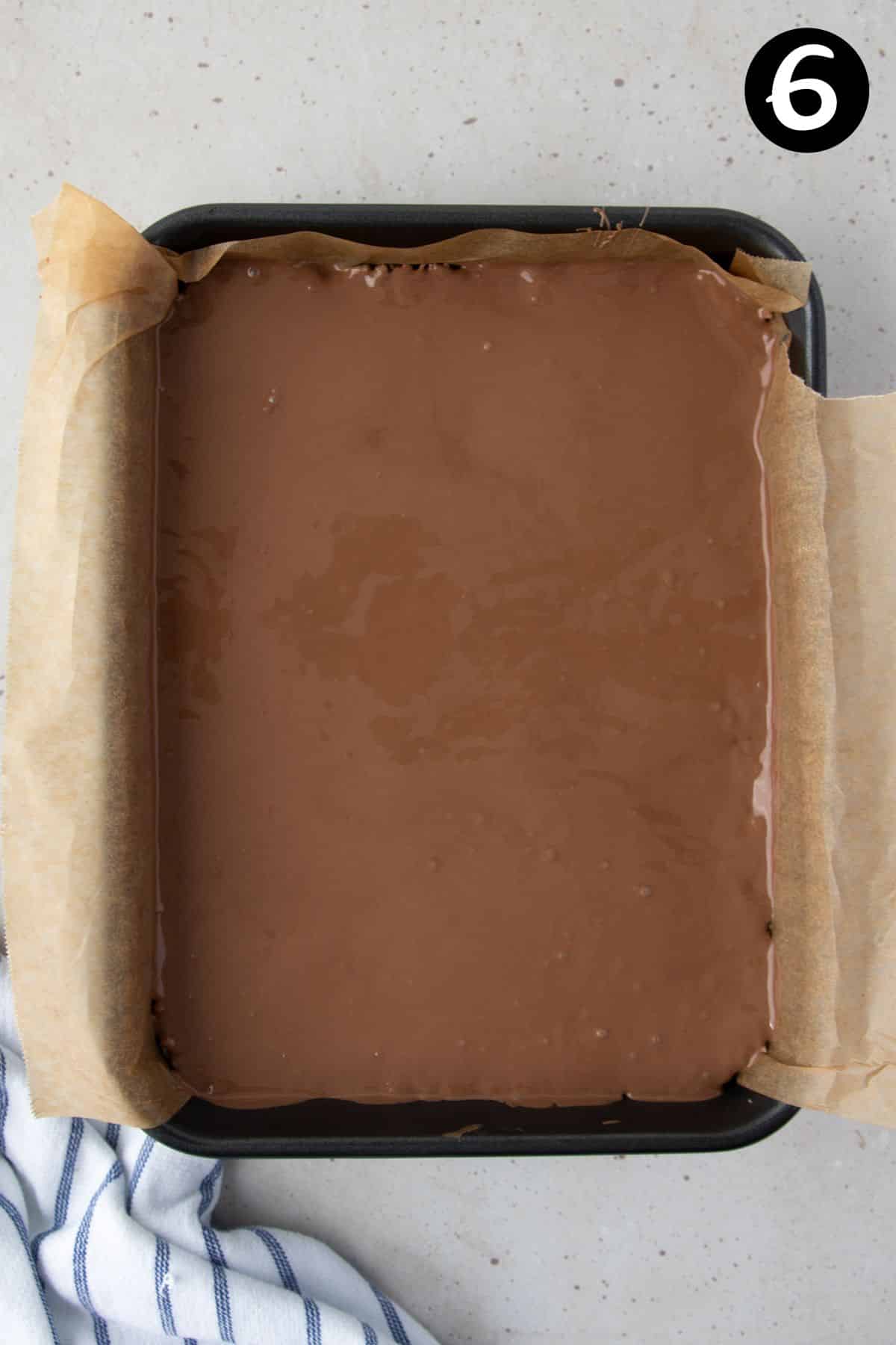 melted chocolate poured over slice in a tin lined with baking paper.