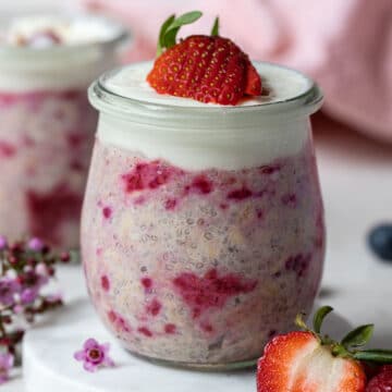 a jar of berry overnight oats topped with yoghurt and fresh berries.