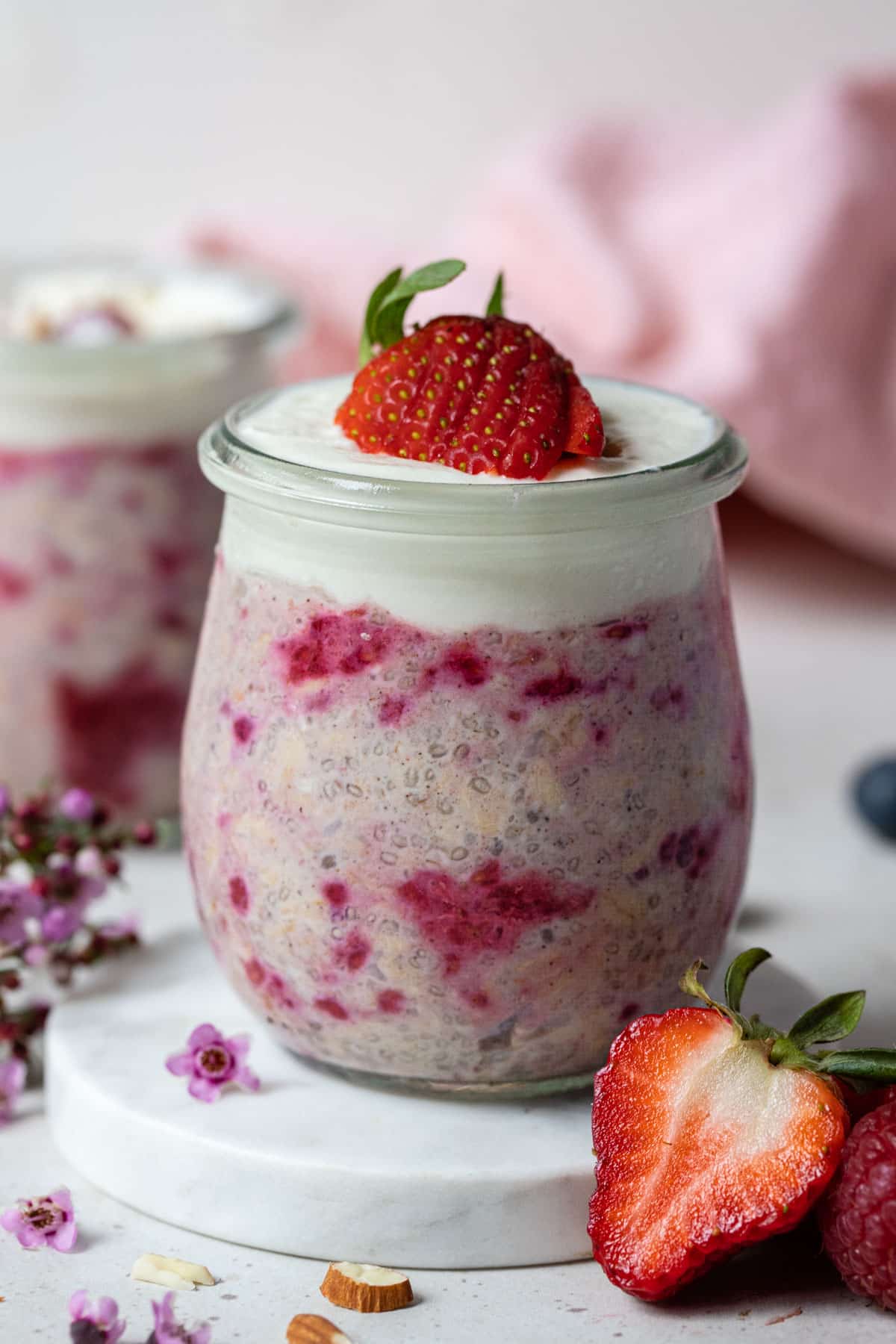 berry overnight oats in a glass jar topped with strawberries and yoghurt.