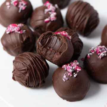 chocolate mint truffles on a white table, one with a bite missing.