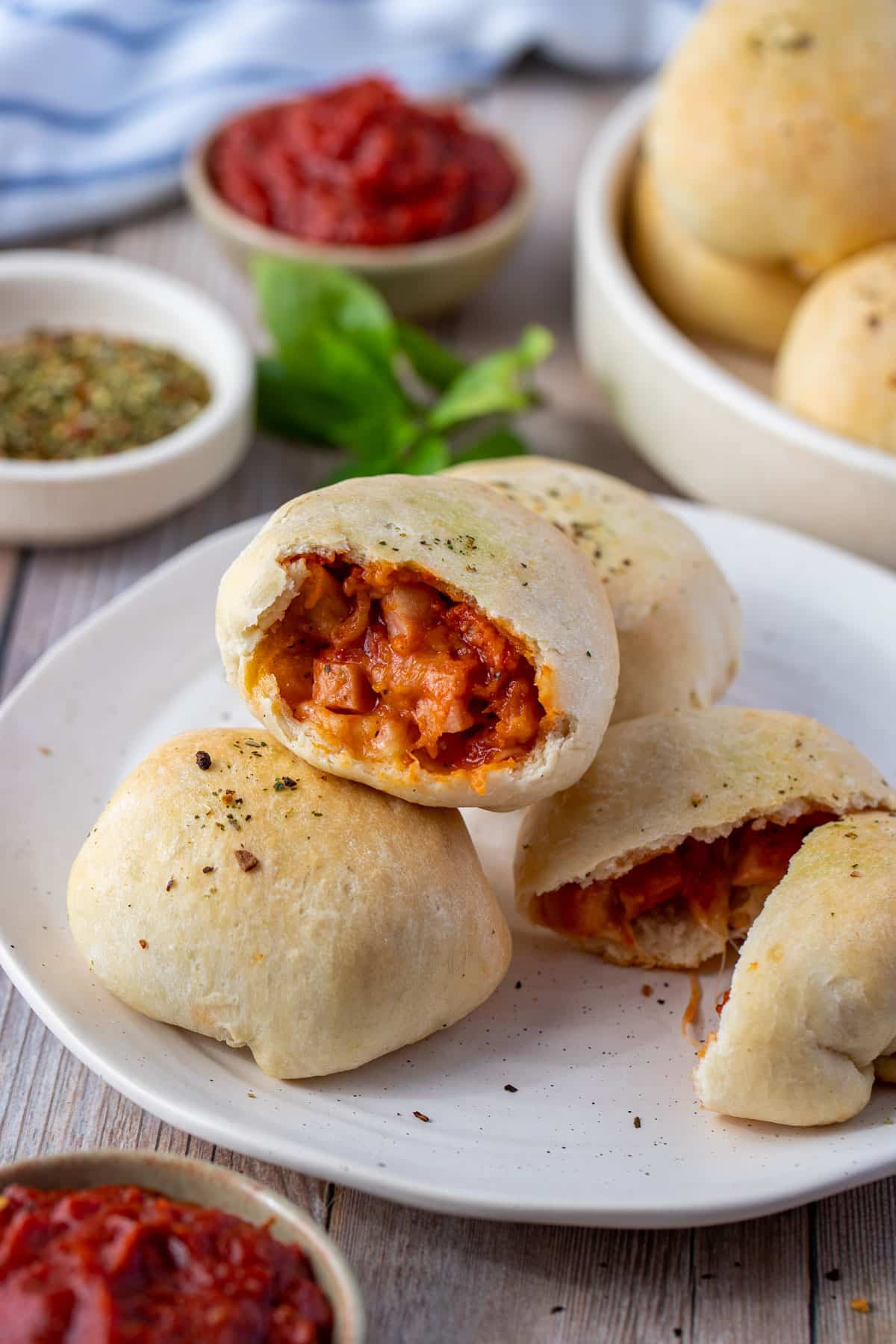 pizza pockets arranged on a white plate with pizza sauce and herbs.