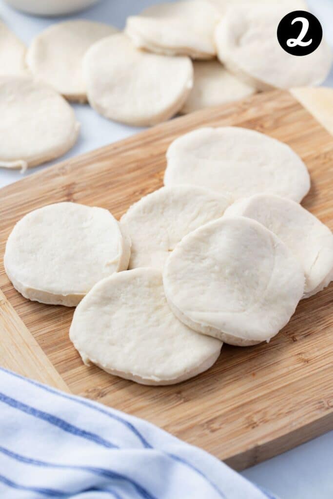 rounds of pizza dough on a wooden board.