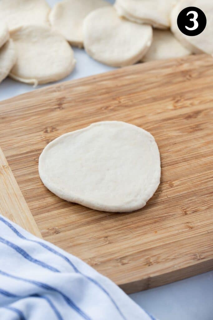 pizza dough, rolled into a circle on a wooden board.