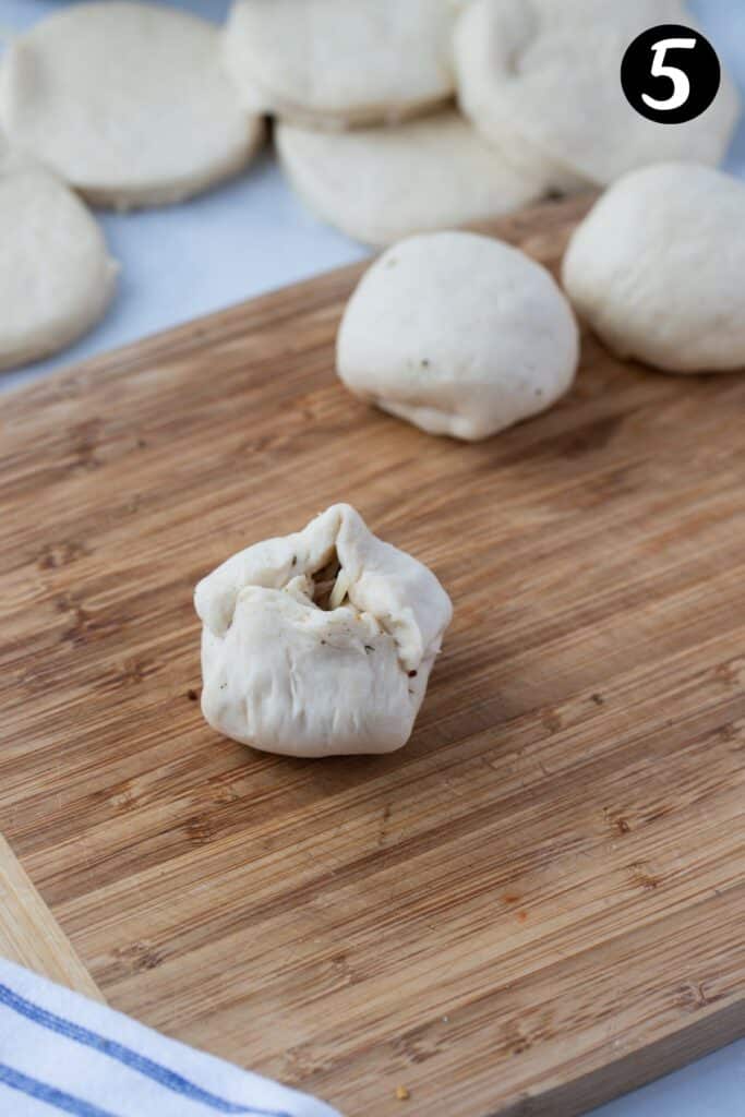 pizza dough being shaped into a ball.