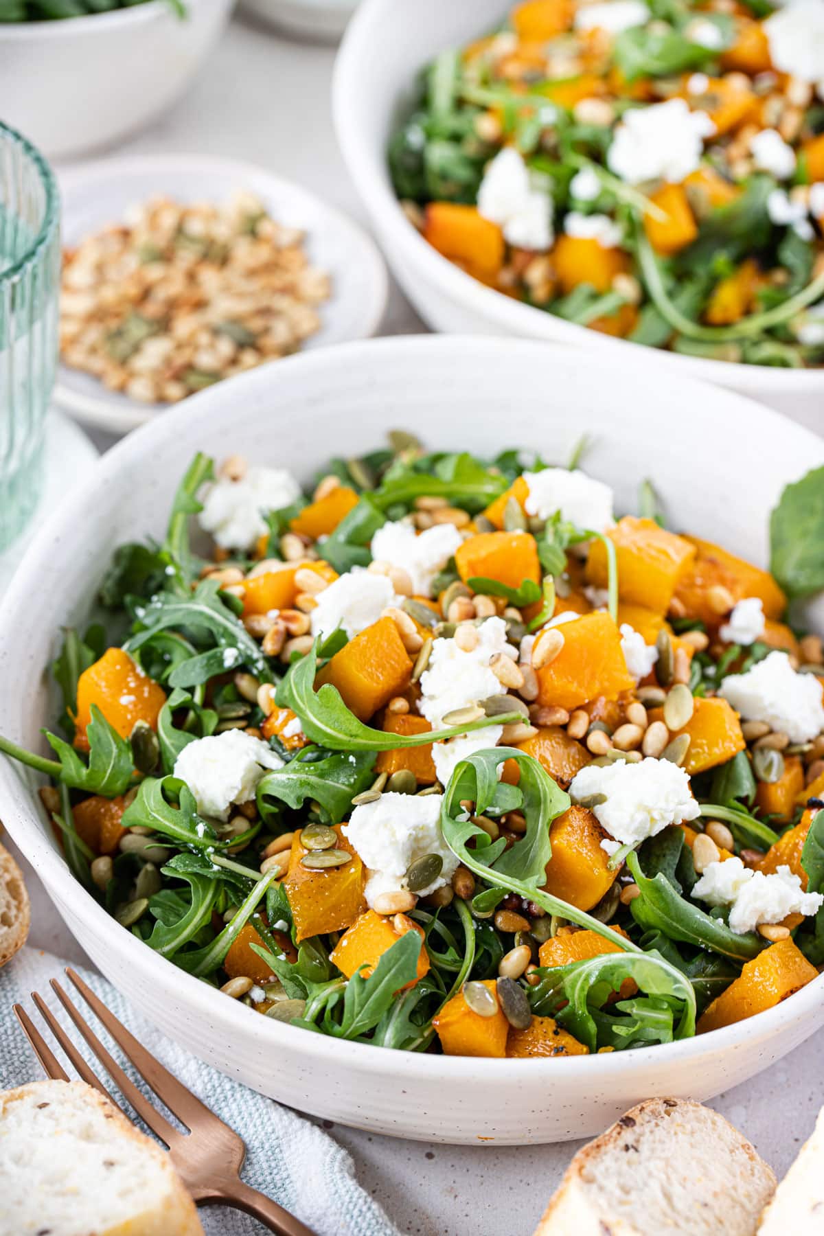 a bowl with rocket, roasted pumpkin and pine nuts, topped with goat cheese.