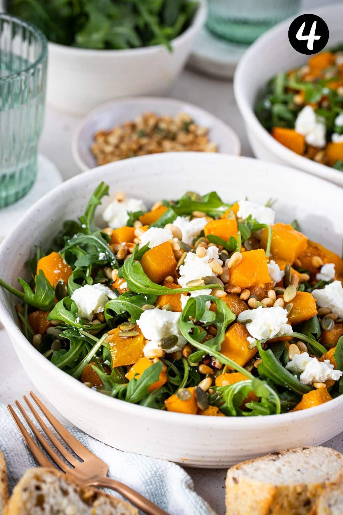 a bowl of roast pumpkin salad topped with pine nuts and goat cheese.