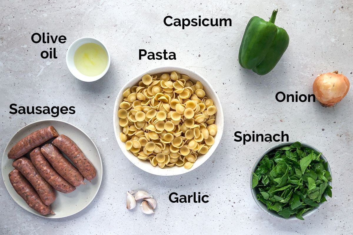 ingredients for sausage pasta, laid out on a table.