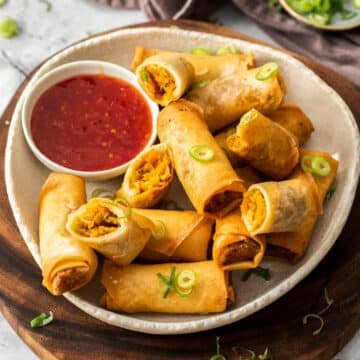 a plate of spring rolls with a dish of sweet chilli sauce.