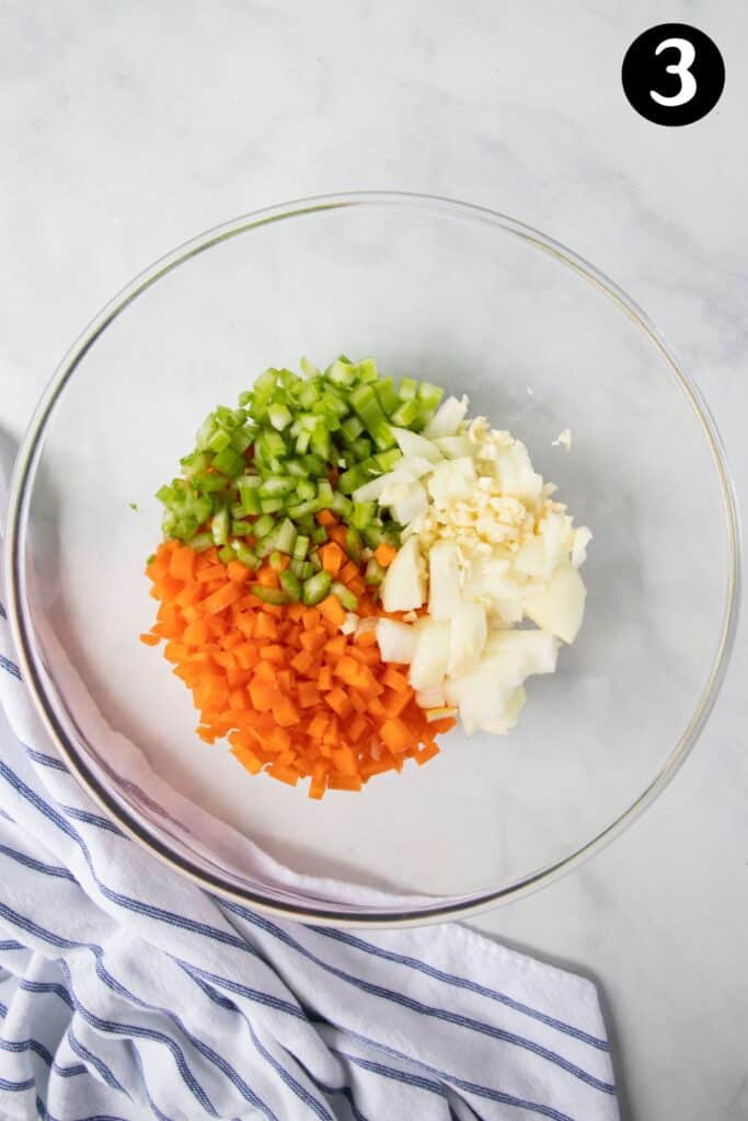 diced celery, carrot, onion and garlic in a bowl.