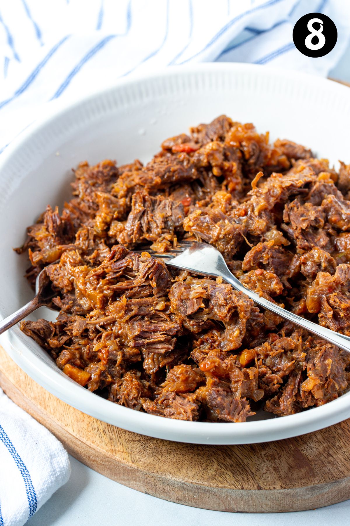 shredded beef cheeks in a bowl with forks.