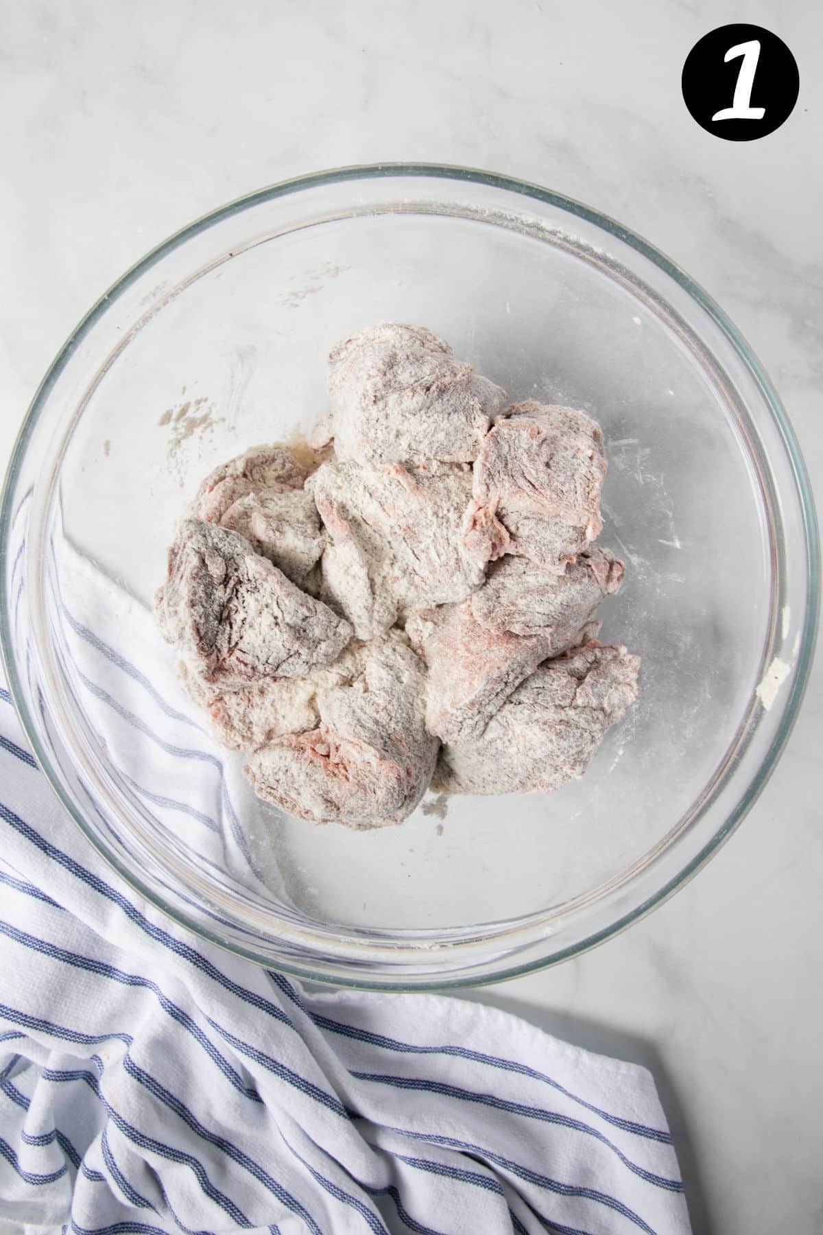 beef cheeks coated in flour in a bowl.