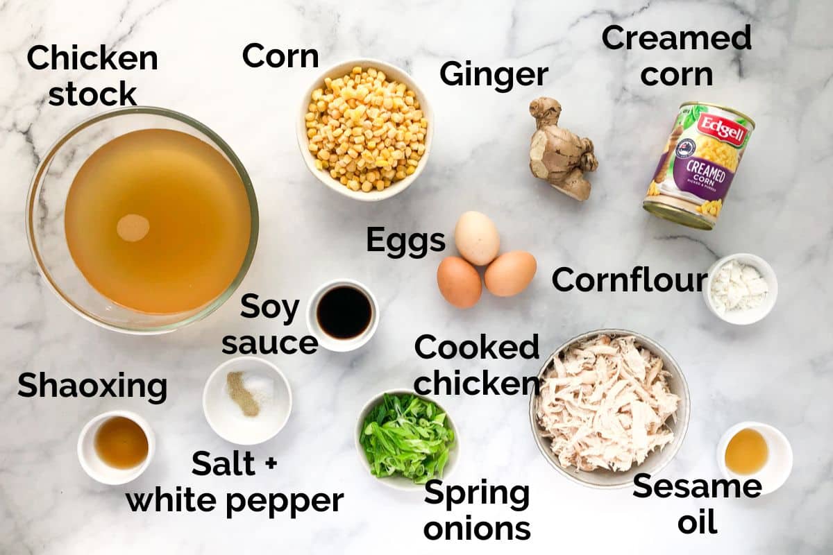 all ingredients for chicken and corn soup, laid out on a table.