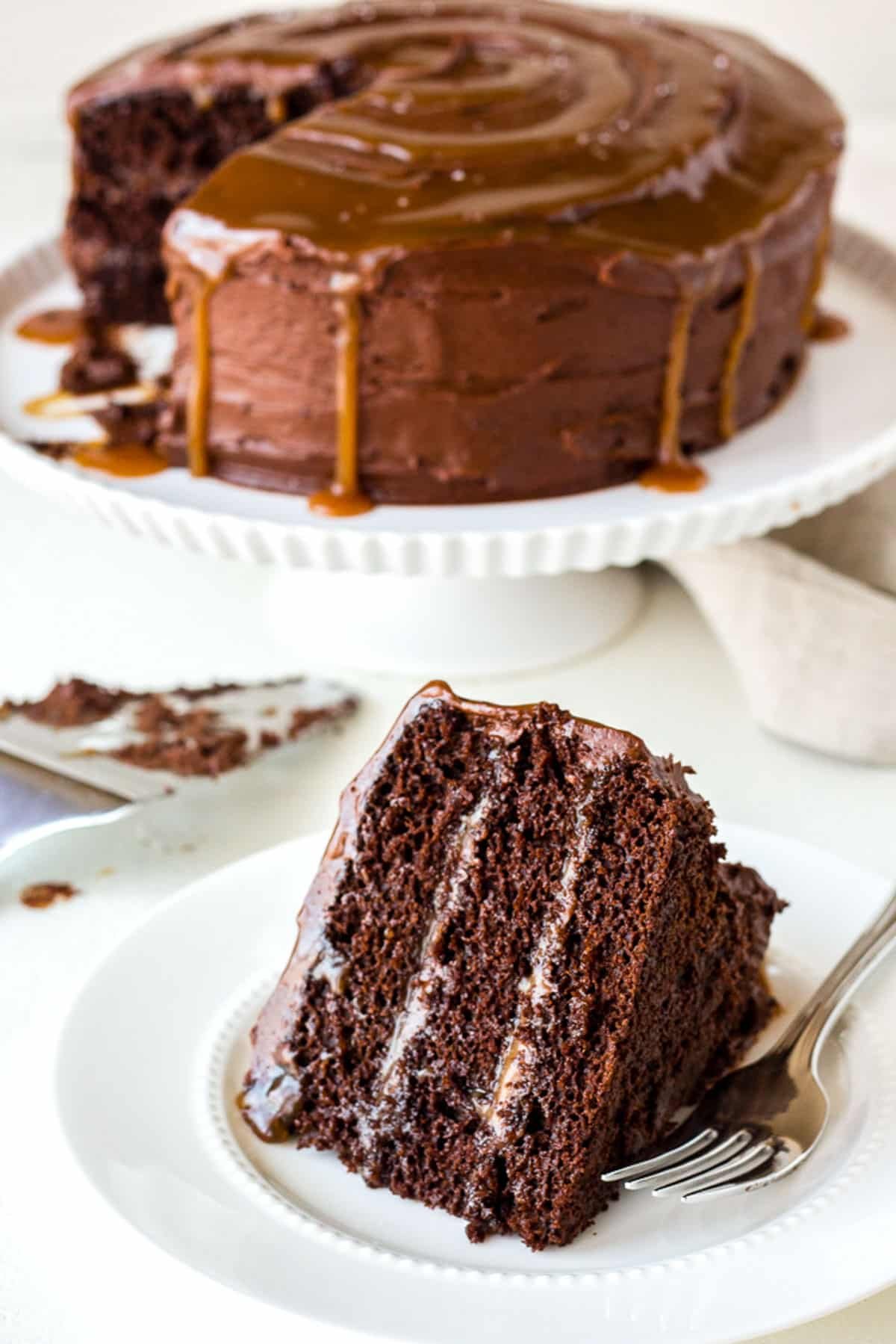 a piece of chocolate caramel layer cake on a plate with a fork.