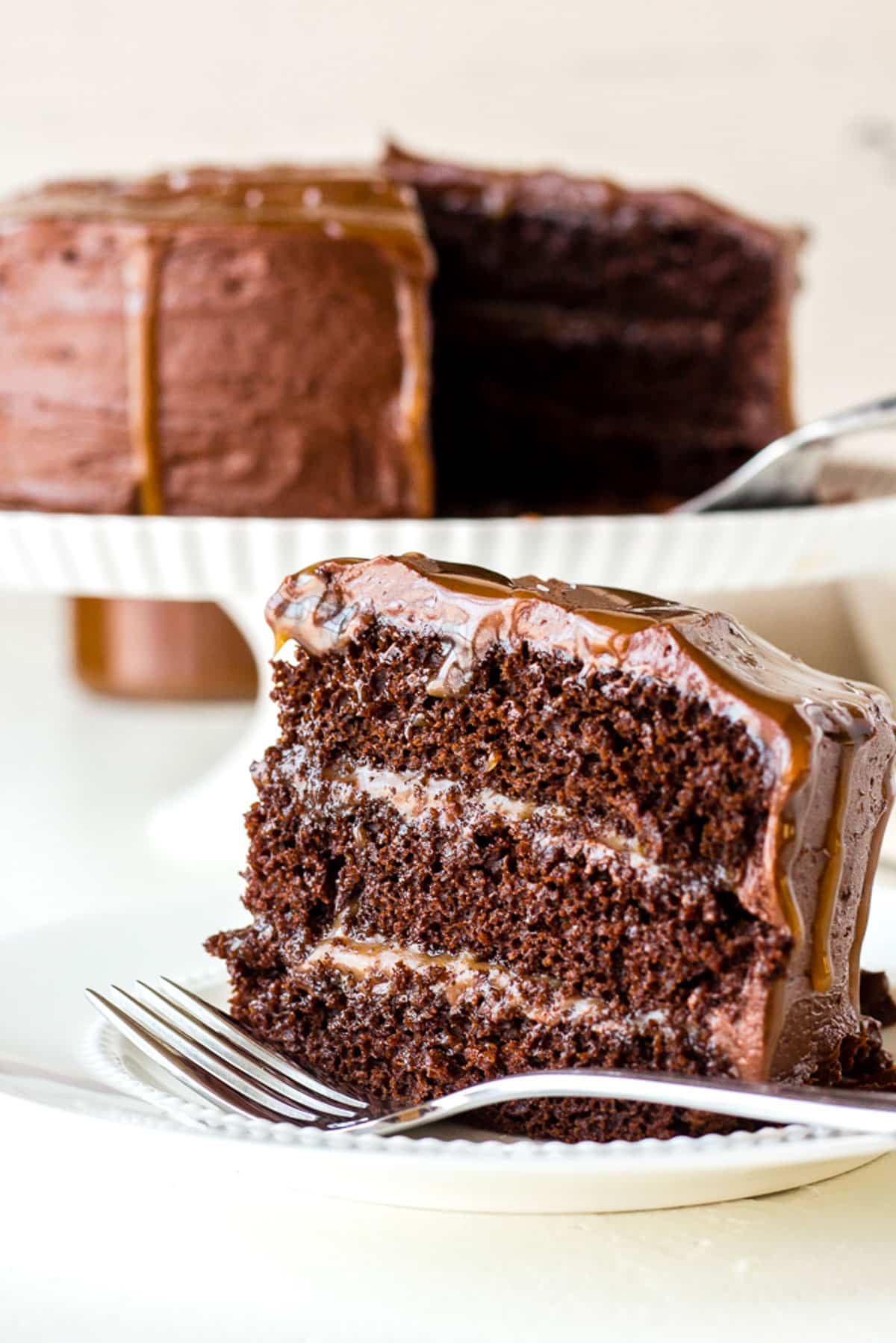 a piece of chocolate cake topped with caramel sauce on a white plate.