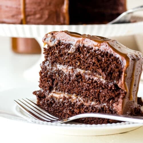 a piece of chocolate caramel cake on a white plate with a fork.