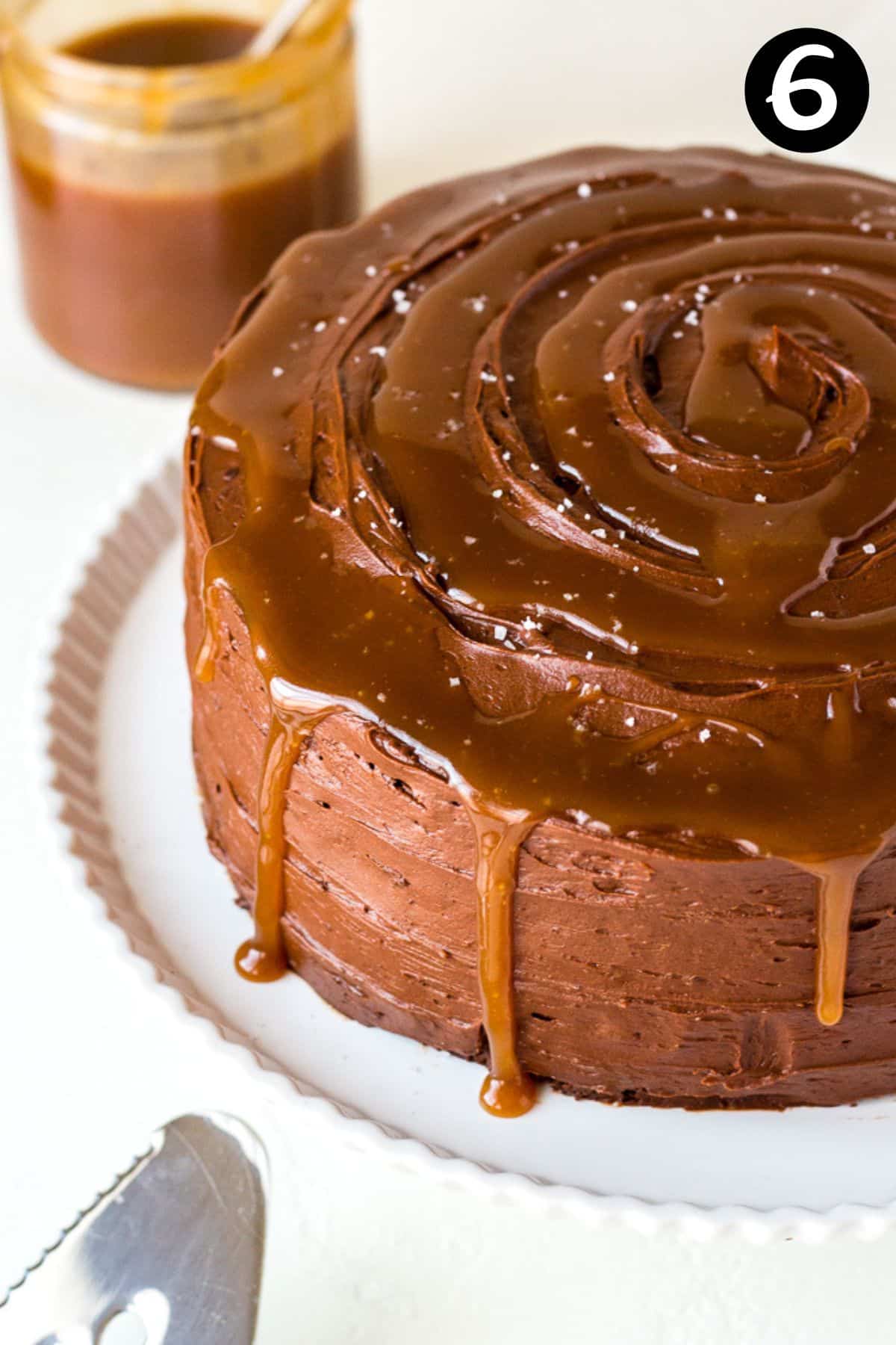 a finished cake topped with frosting, with caramel sauce dripping down the sides.