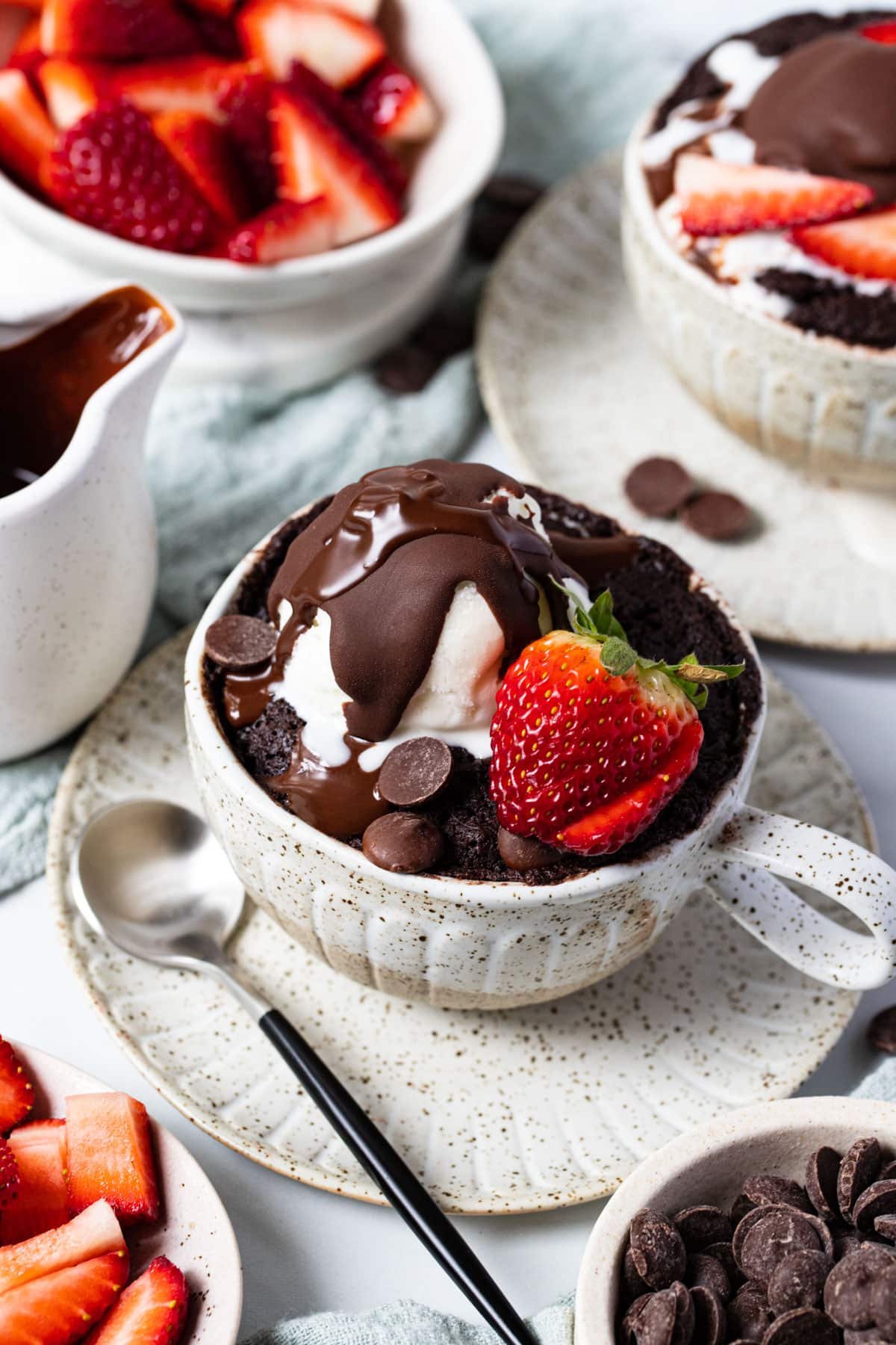 chocolate mug cake on a table with berries and ice cream.