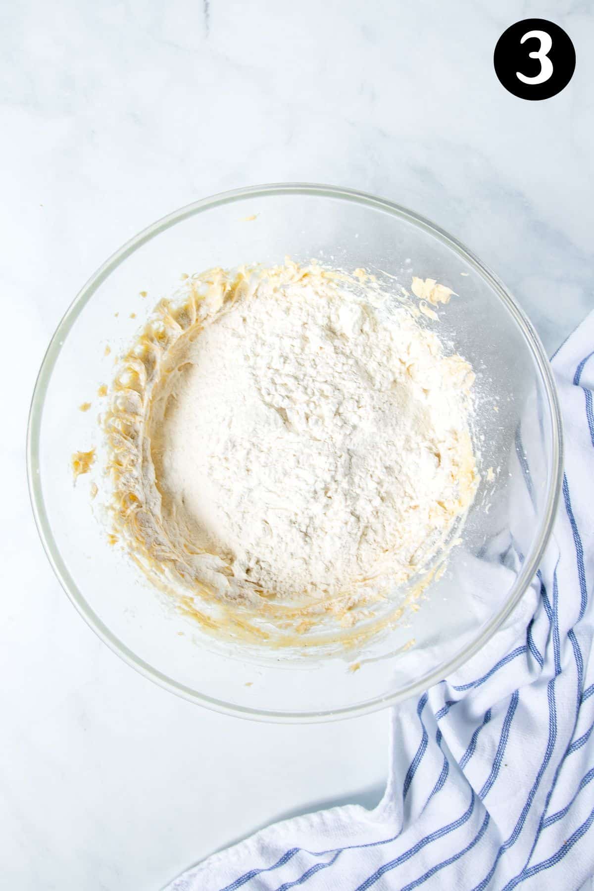 flour and cornflour added to butter mixture in a bowl.