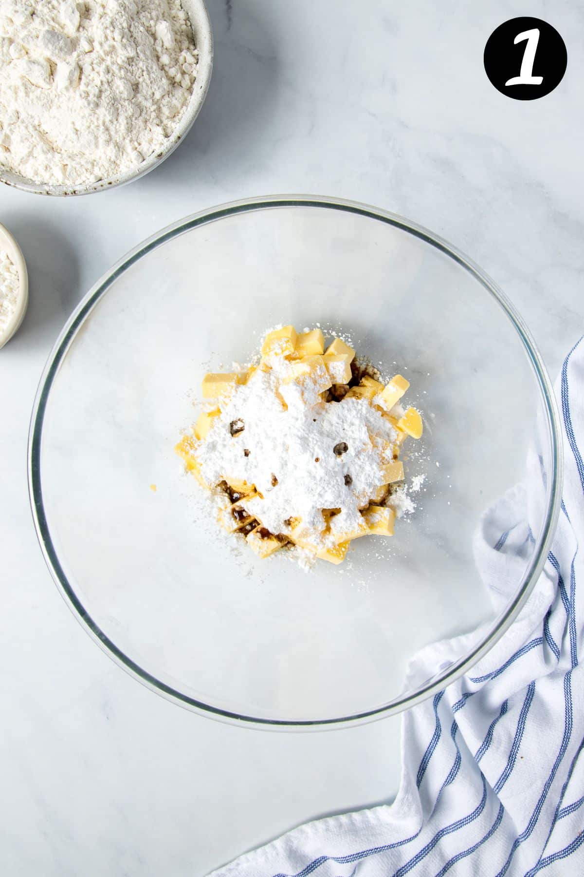 a mixing bowl containing butter, icing sugar and vanilla.