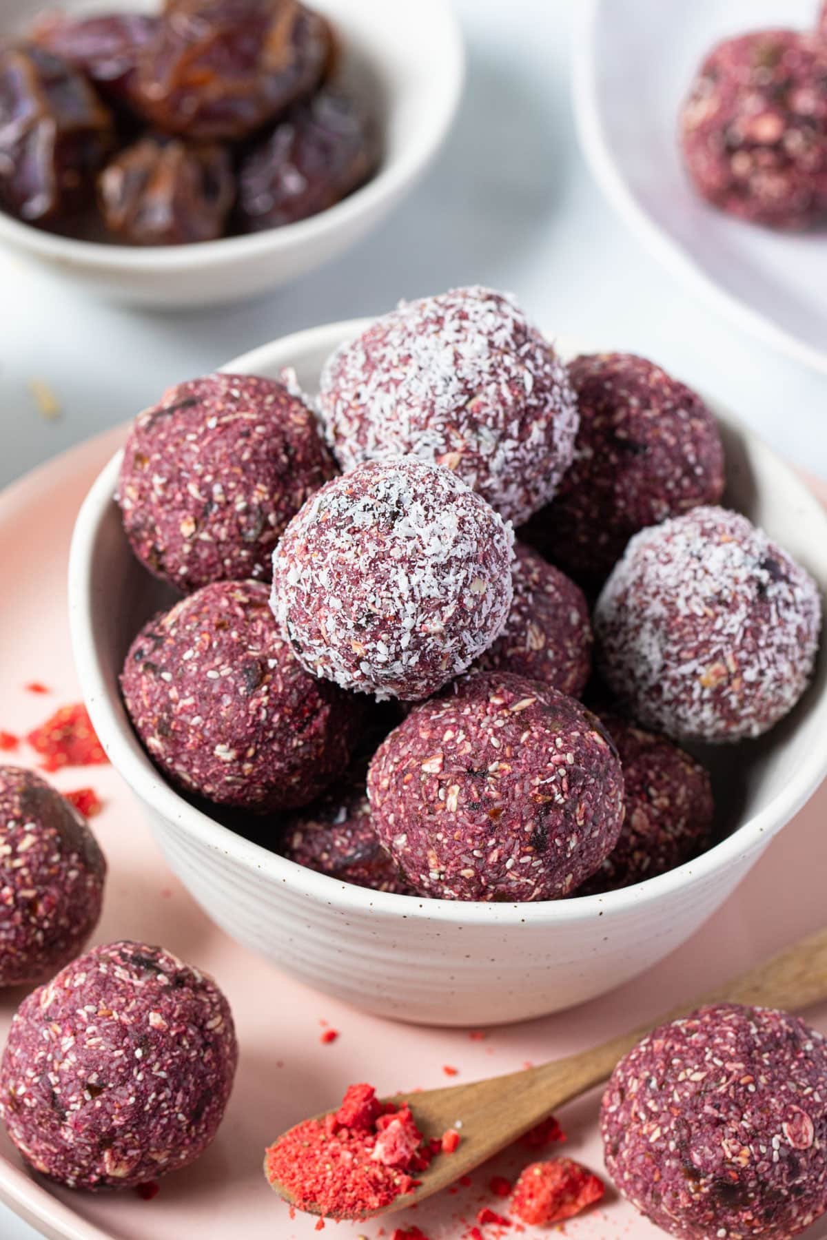 bliss balls coated in coconut in a white bowl.