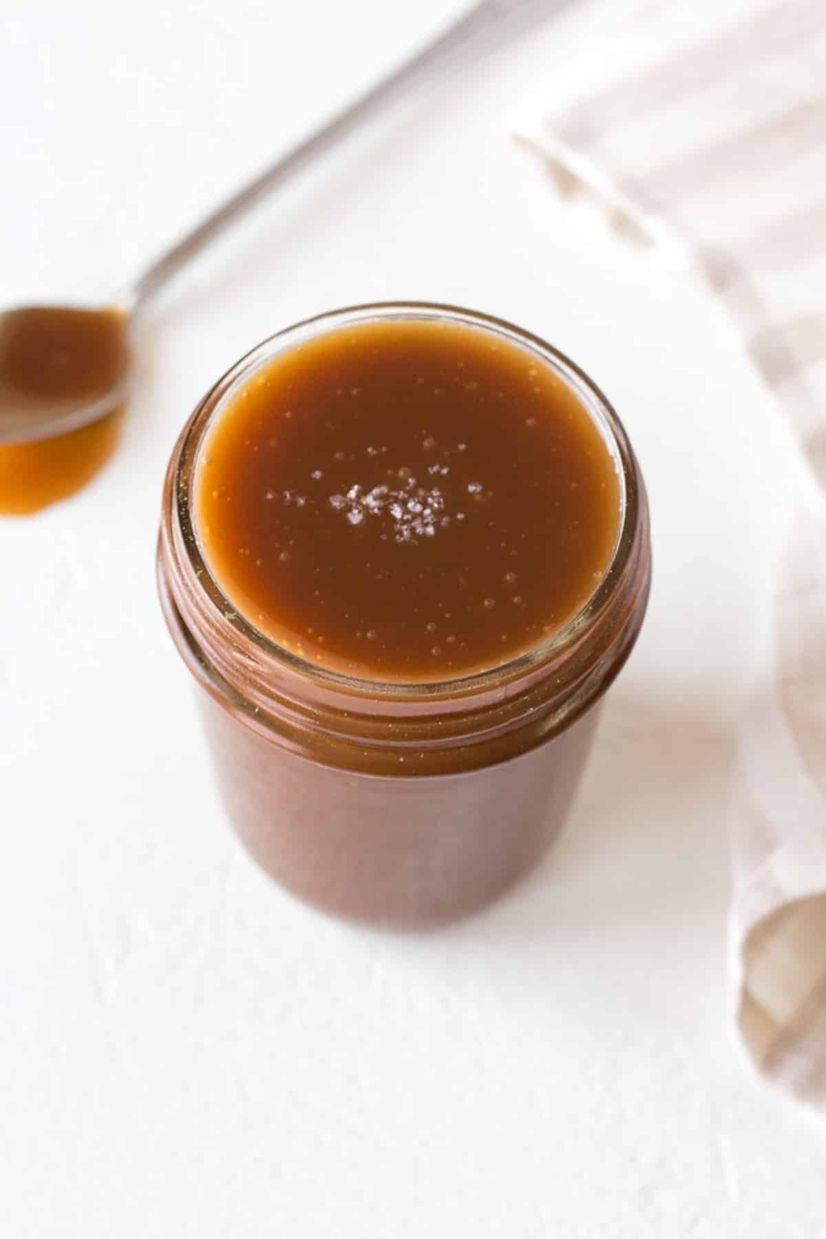 a jar of caramel sauce topped with salt flakes.