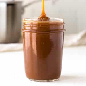 a jar of salted caramel sauce on a white bench.