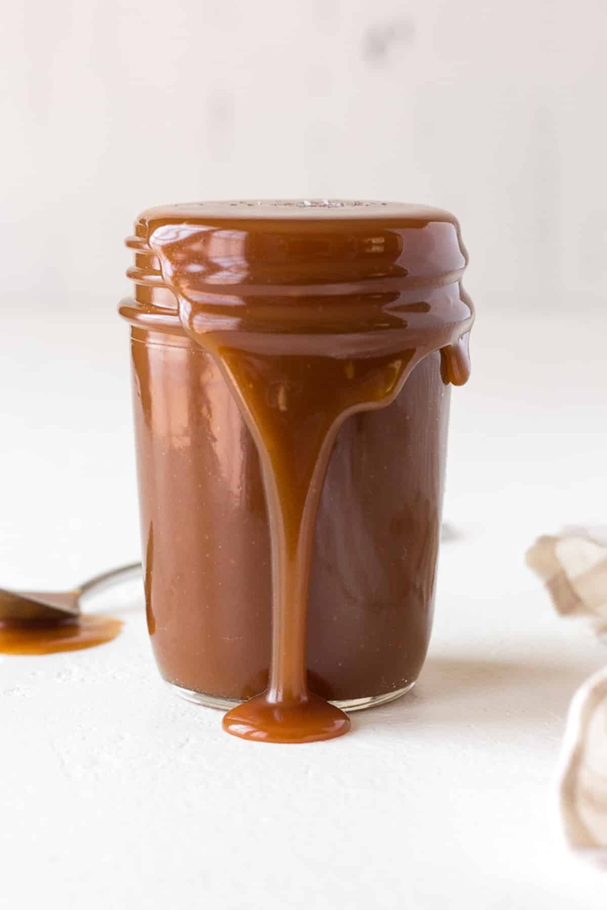 a jar of salted caramel sauce. The sauce is running over the side of the jar.