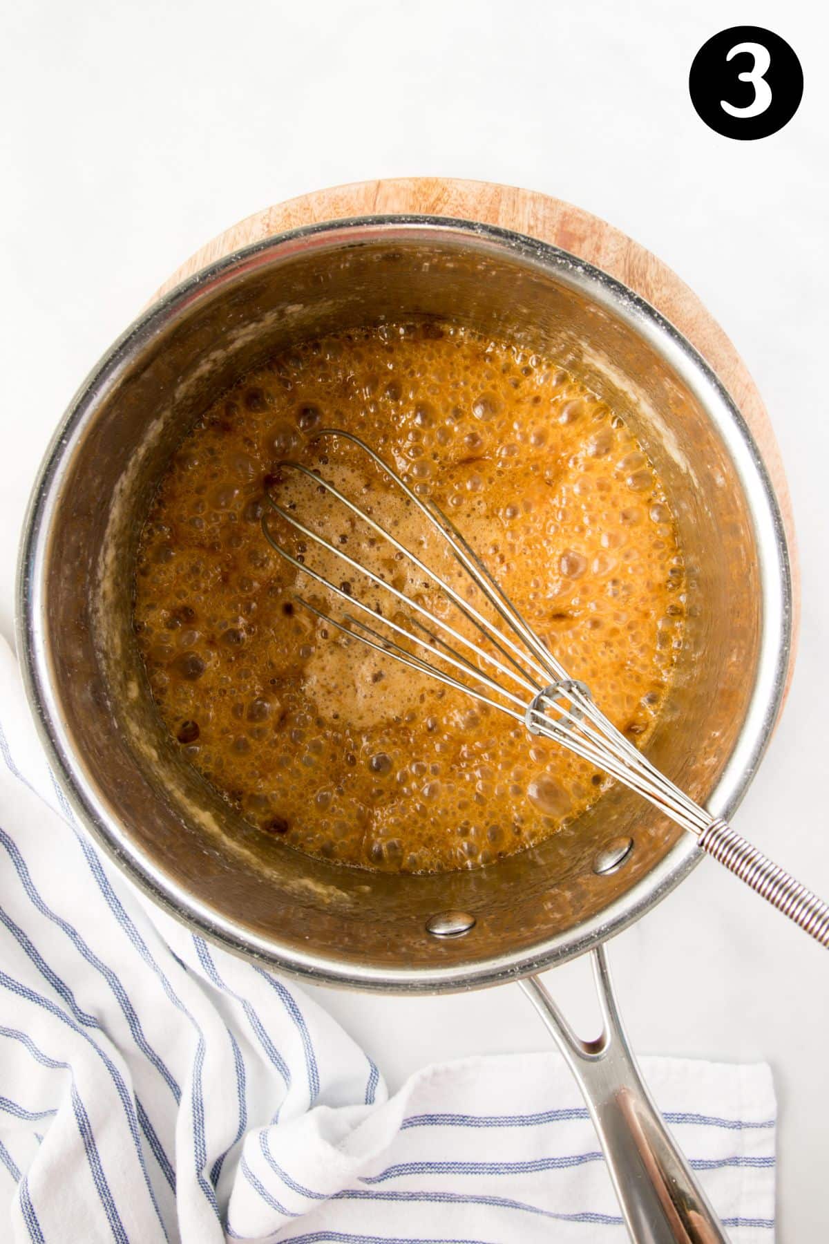 butter added to caramel in a pan. It is bubbling around a whisk.