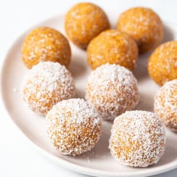 orange coloured apricot balls rolled in coconut, on a white plate.