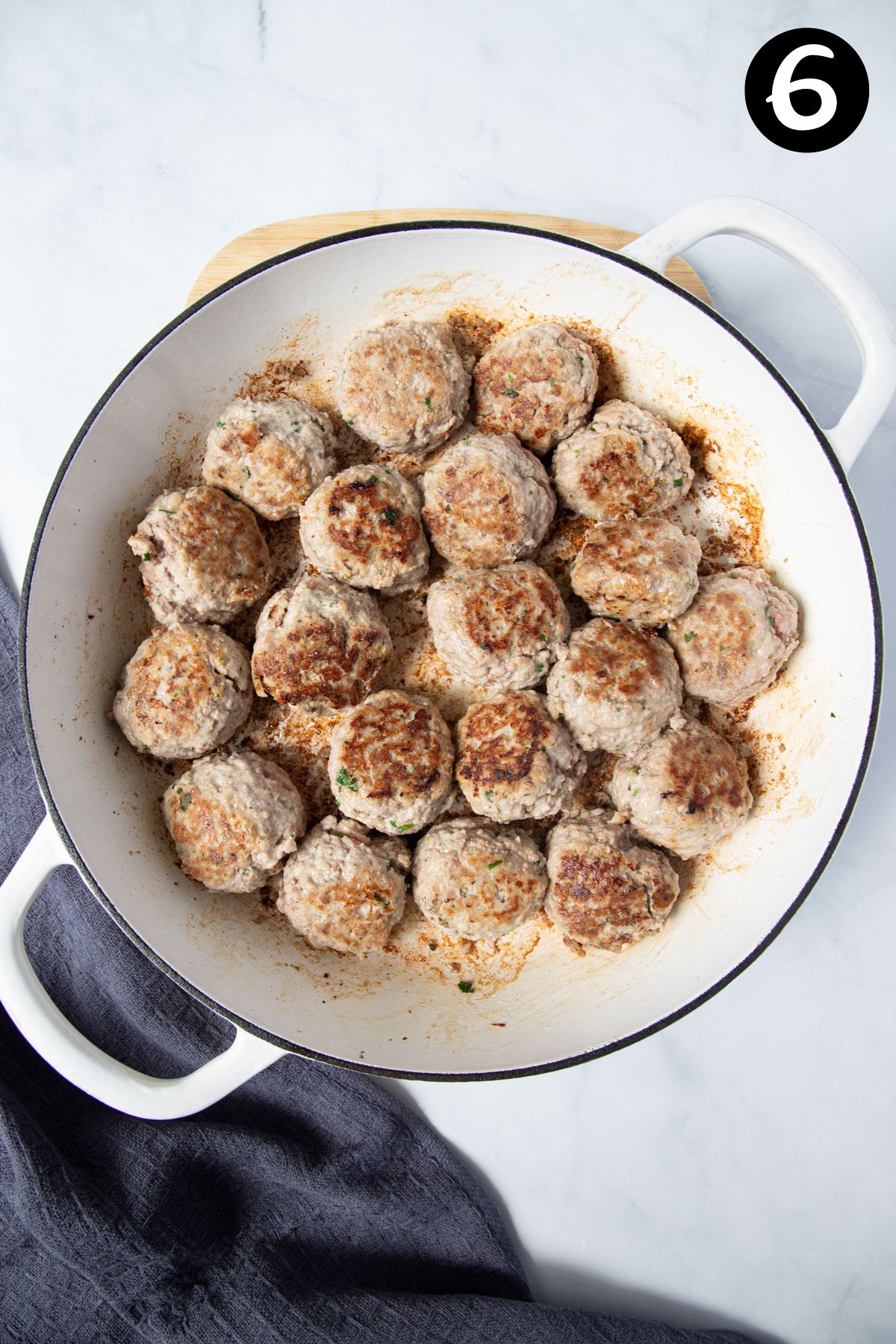 browned meatballs with a golden outer crust in a French pan.