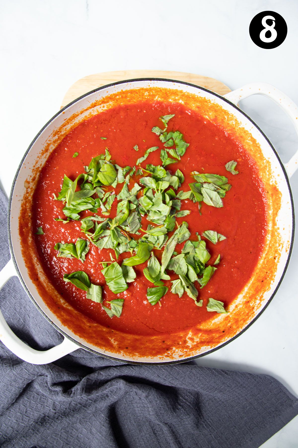 red tomato sauce topped with basil in a pan.