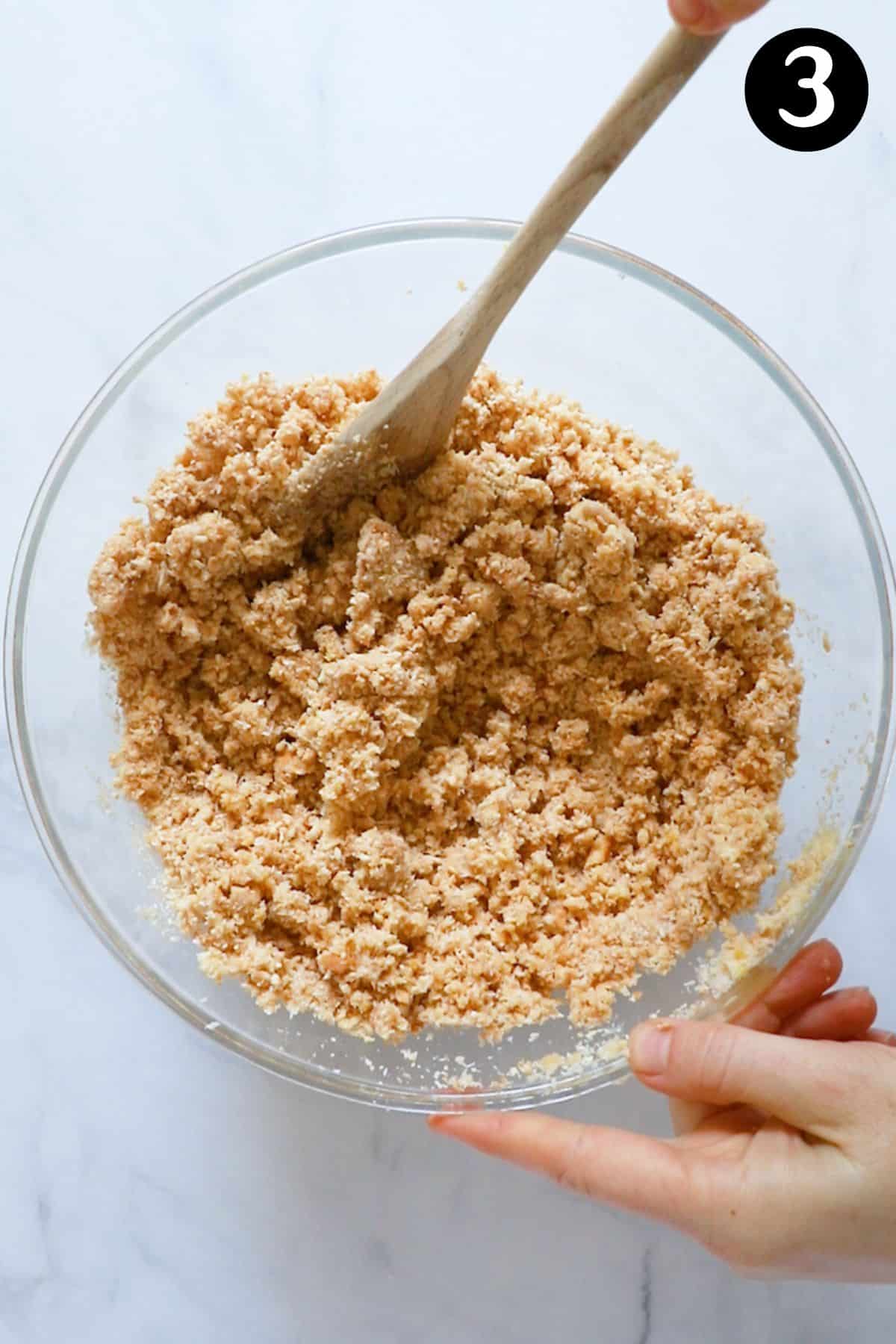 a spoon stirring the biscuit base ingredients in a bowl.