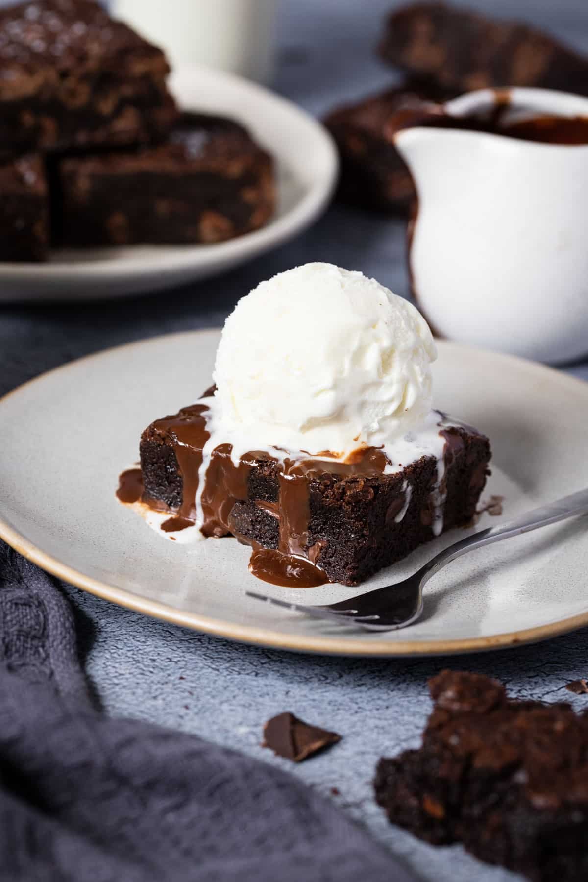 a chocolate brownie on a plate topped with a scoop of ice cream.