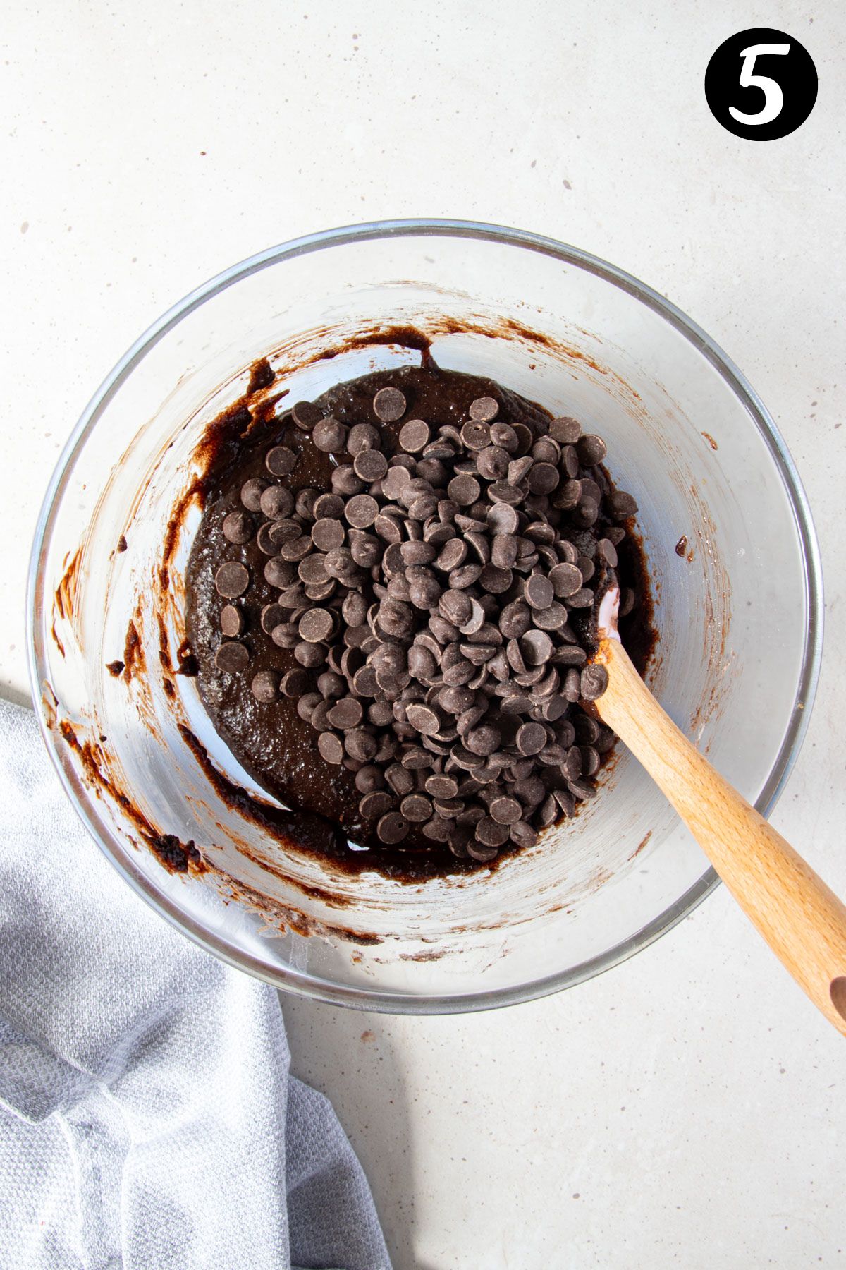 chocolate chips added to brownie mixture in a glass bowl.