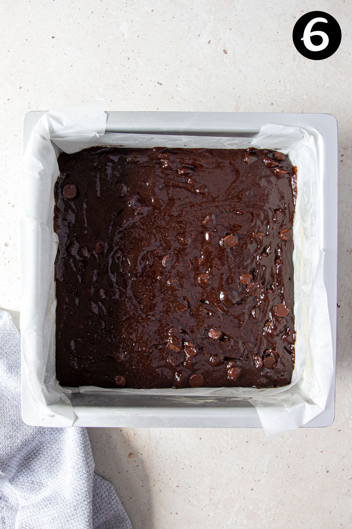 brownie batter in a square baking tin lined with paper.
