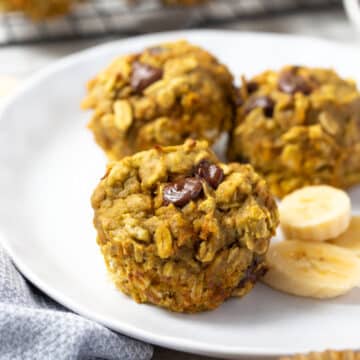 muffins on a white plate with chocolate chips and slices of banana.