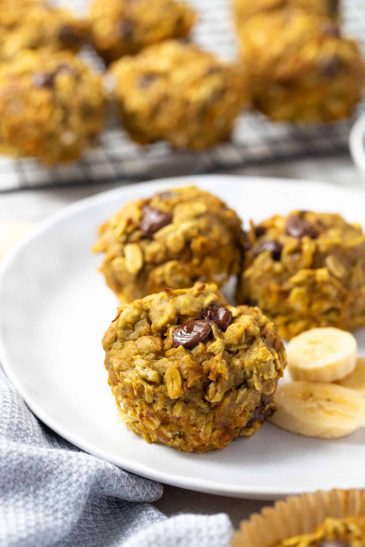 abc muffins topped with melted chocolate chips on a plate with sliced bananas.