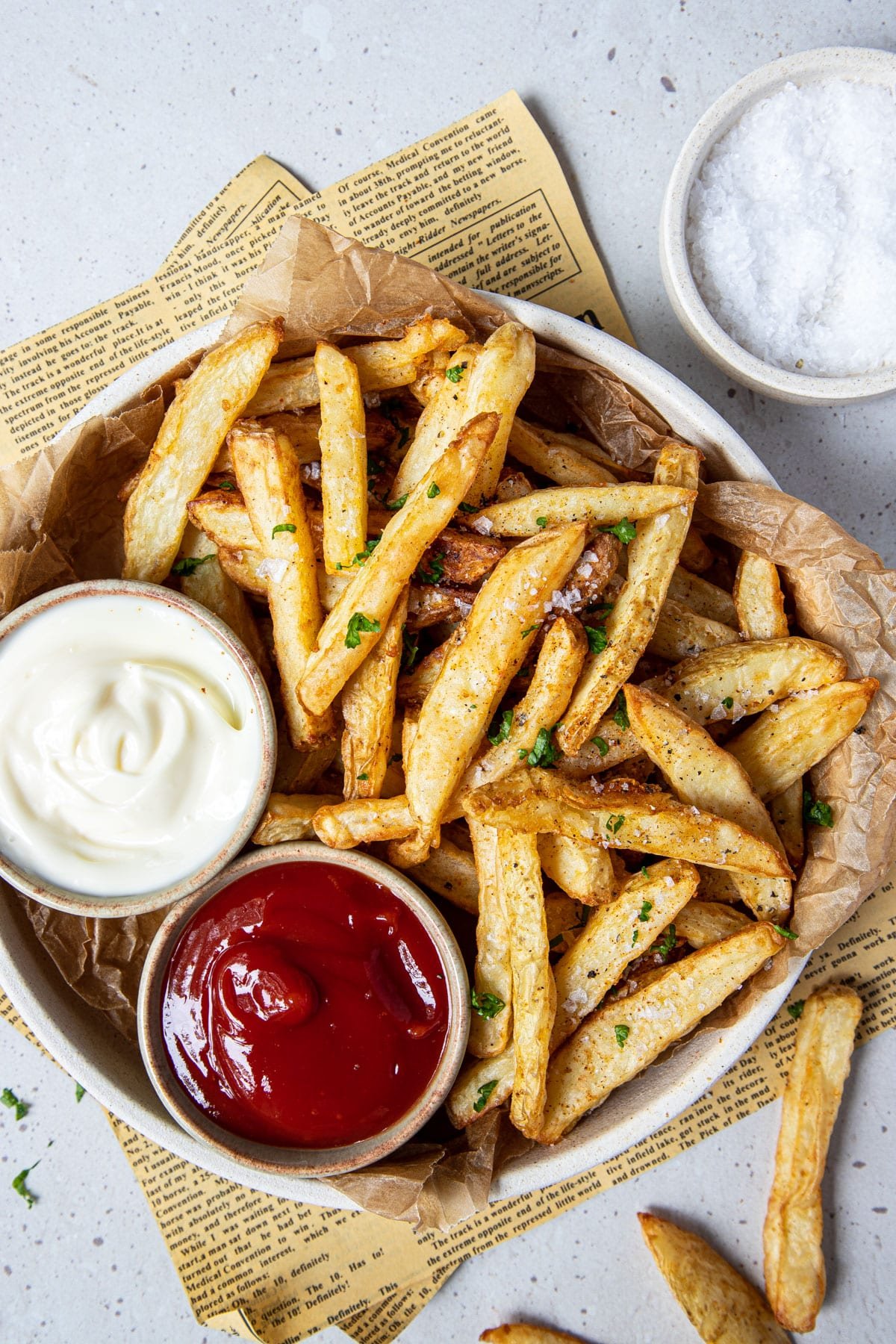 potato chips in a bowl with dishes of dipping sauce.