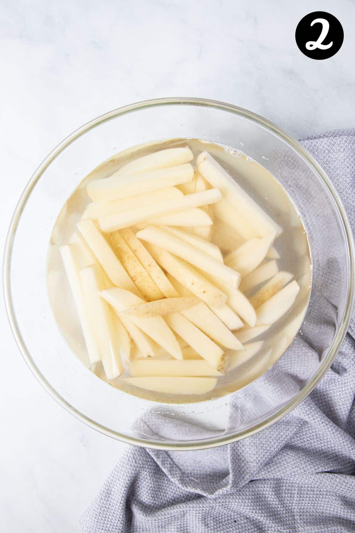 chips soaking in a glass bowl filled with water.