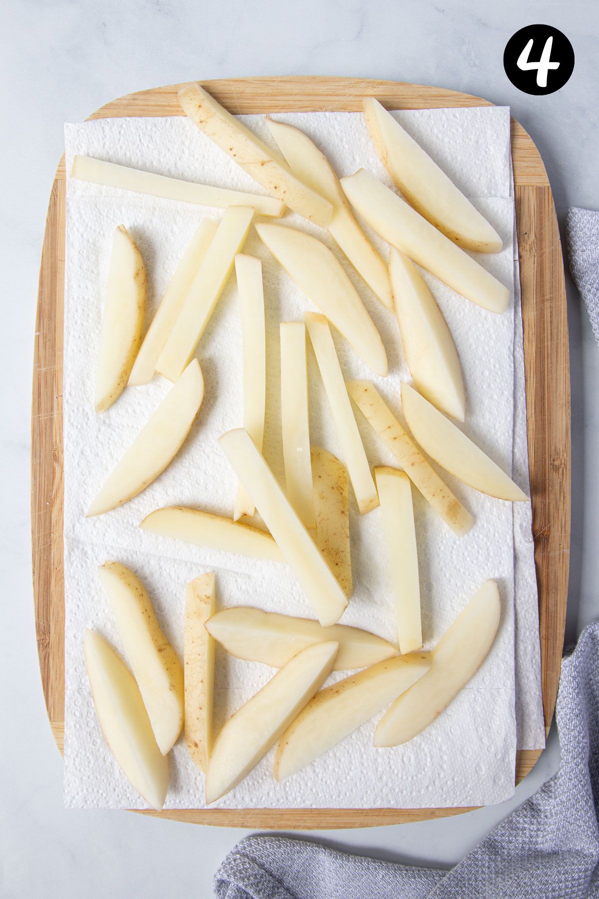 potato chips resting on a board lined with paper towel.