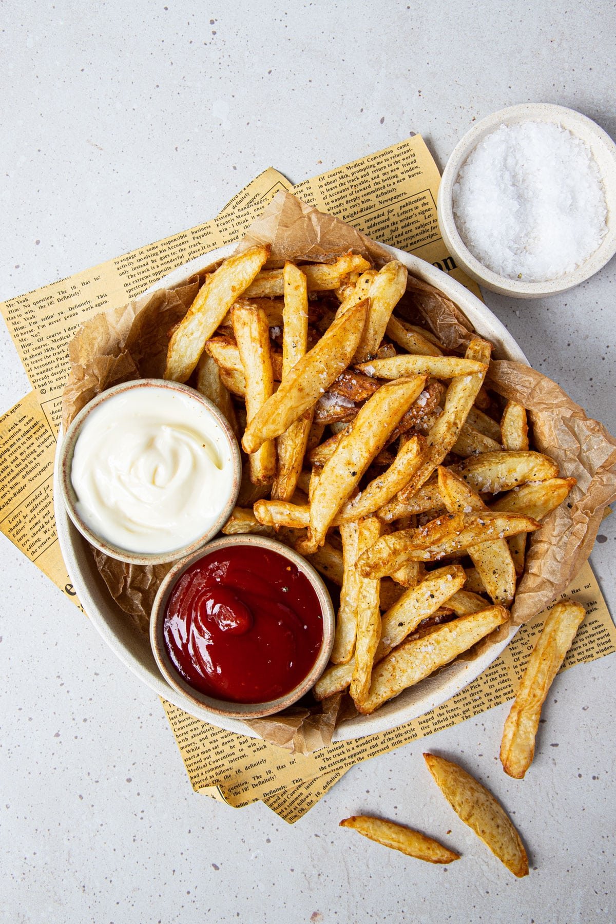 a bowl of chips on a table, with bowls of dipping sauces.