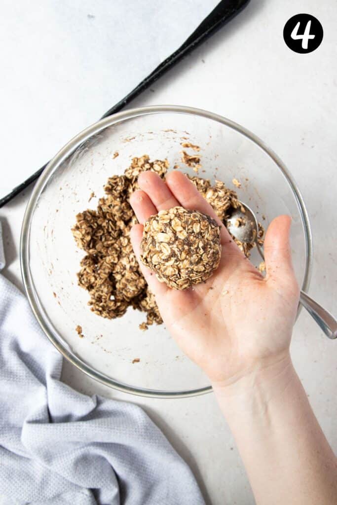 a hand holding an uncooked oat cookie.