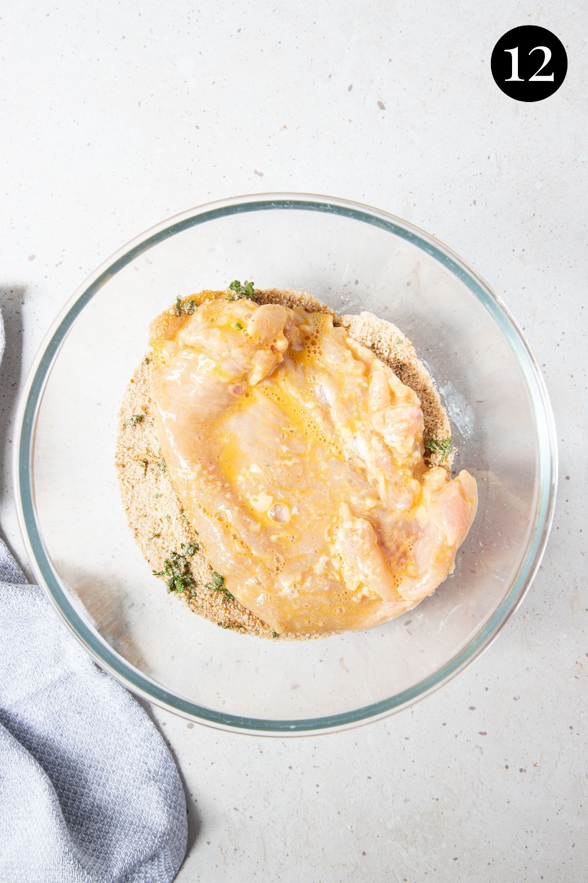 chicken in a bowl being coated in breadcrumbs.