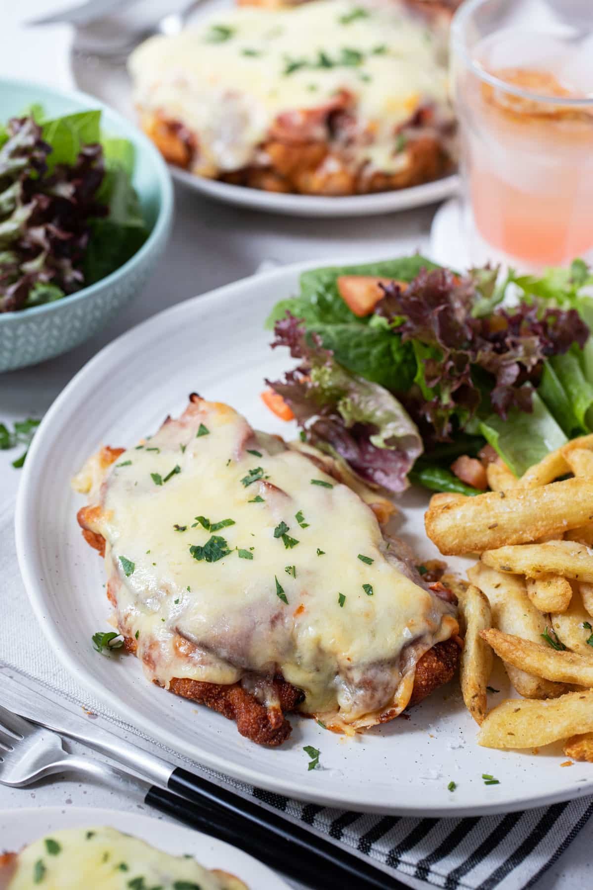 a plate with chicken parmigiana, chips and salad