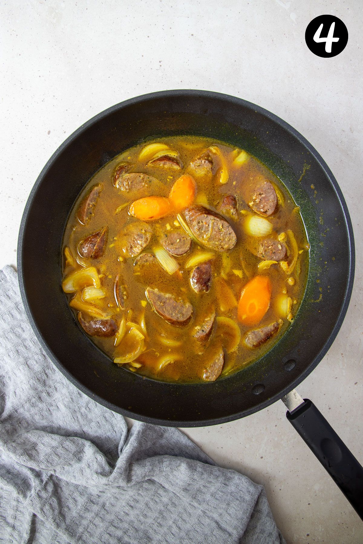 stock and curry powder with vegetables in a pan.